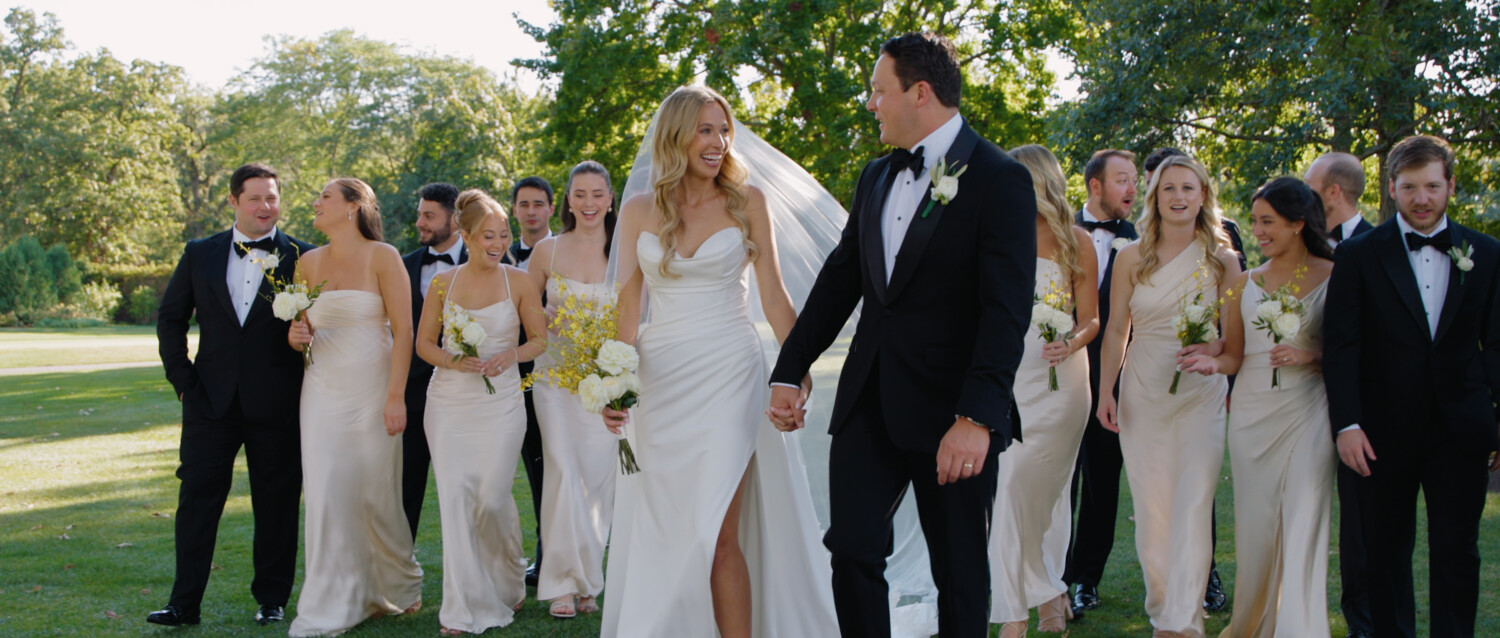 bride and groom walking with wedding party behind them
