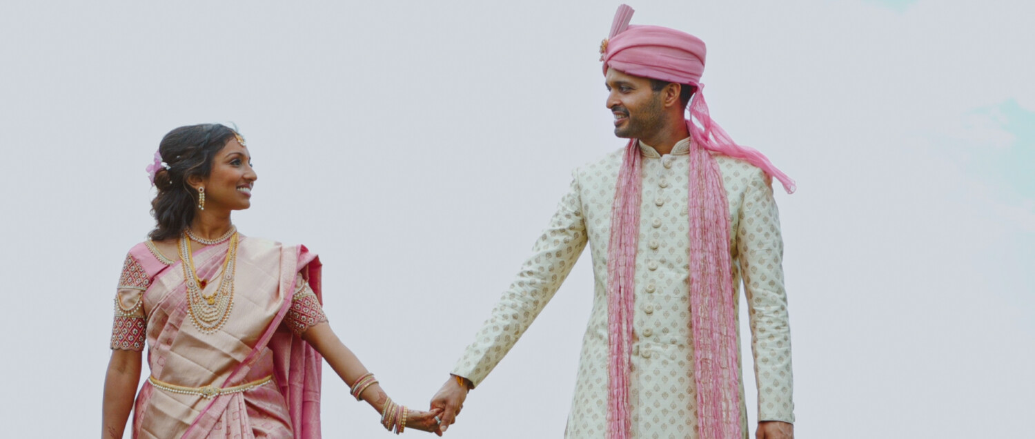 indian couple holding hand with the jw marriott behind them