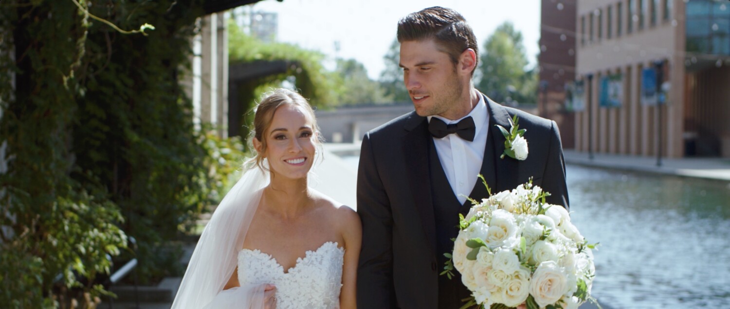 bride and goorm walking outside of the indiana state museum near canal